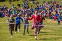 Girl in Highland dancer outfit crossing finishing line in girls race