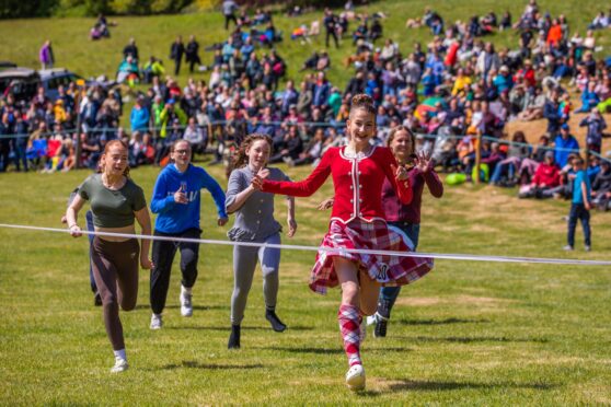 Girl in Highland dancer outfit crossing finishing line in girls race