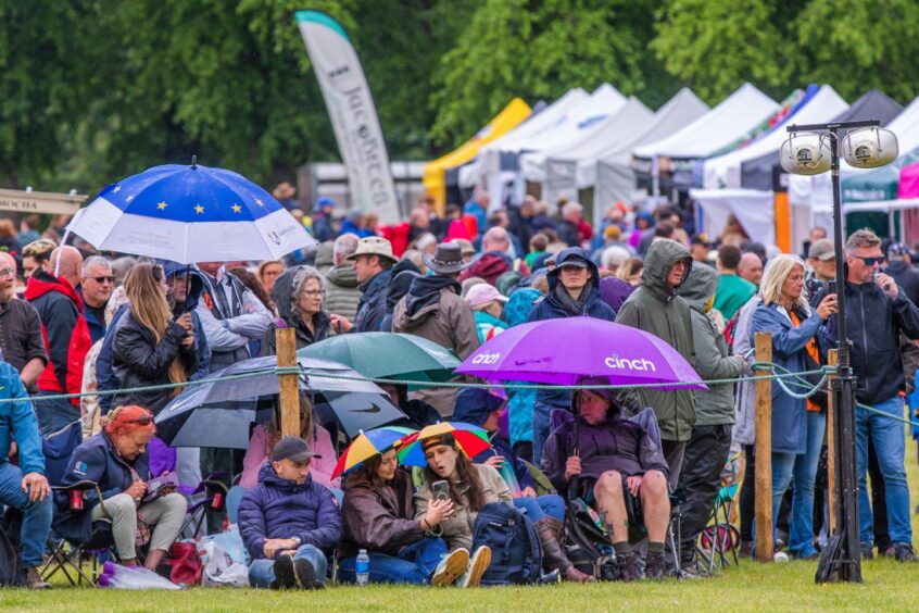 Crowd watching action under umbrellas in the rain