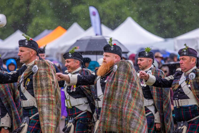 Men in Highland dress marching in rain at Atholl gathering