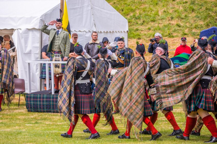 Atholl Highlanders in traditional highland gear walking past saluting Marquis of Tulliebardine