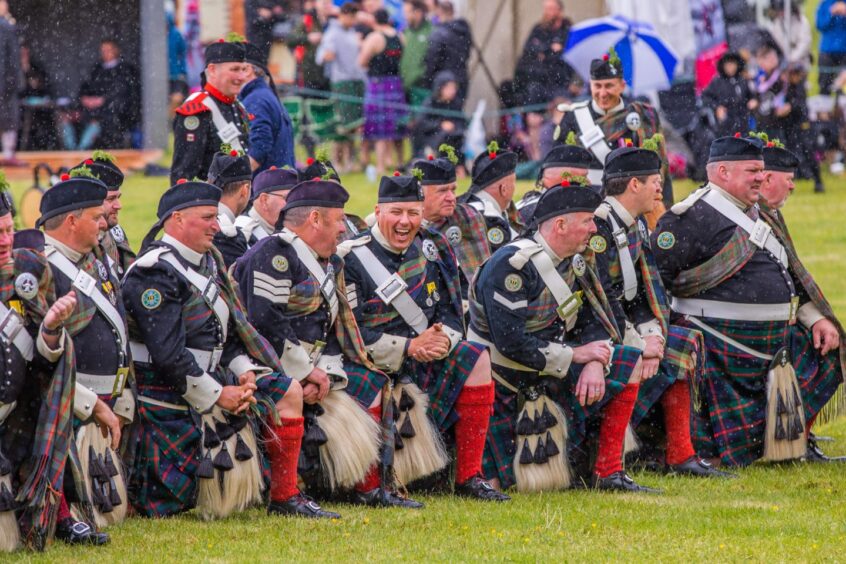 A group of men from the Atholl Highlanders in Highland regalia kneeling on the grassy arena.