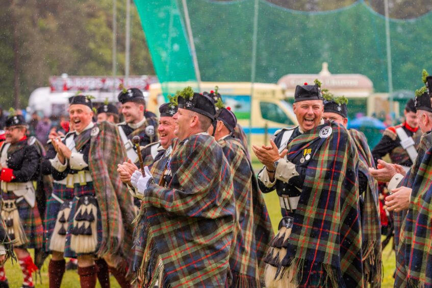 Men in Highland dress smiling and applauding