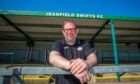 Iwan Davies smiling with Jeanfield Swifts FC stadium behind