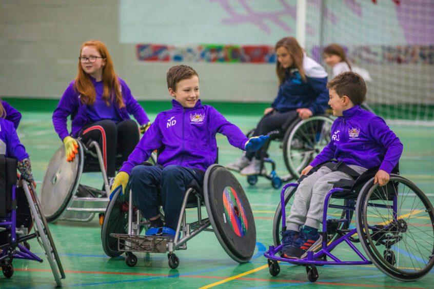 Youngsters in a gym playing wheelchair rugby in Perth.