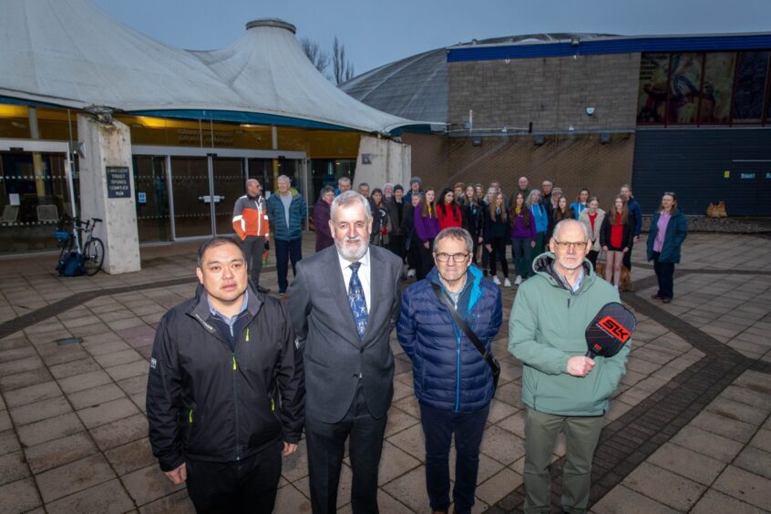 People standing outside Bell's Sports centre, Perth, looking unhappy, one holding a table tennis bat