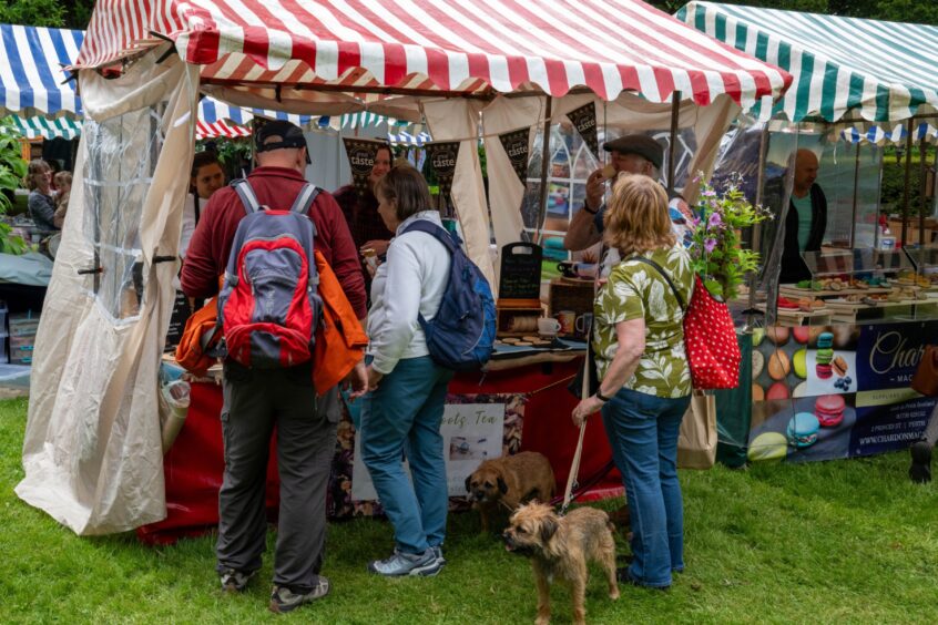 People at stall, one with two border terriers on leads