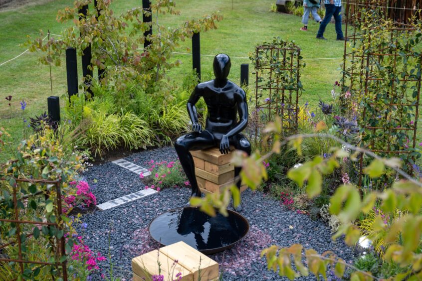Garden with statue of seated figure surrounded by plants