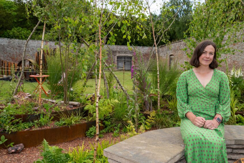 Woman seated on stone bench next to garden display