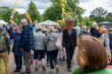 Man walking through crowd in smart suit with flower pot covering face and head