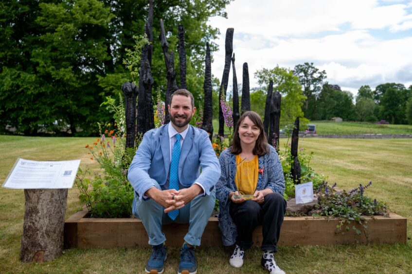 Viscount Stormont seated beside Lizzie Patterson in front of garden display