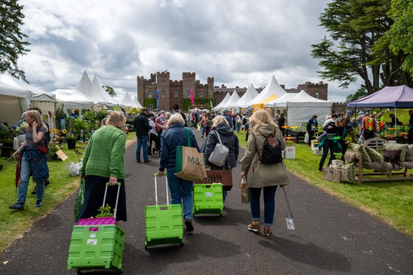 Women pulling wheeled trolleys full of plants