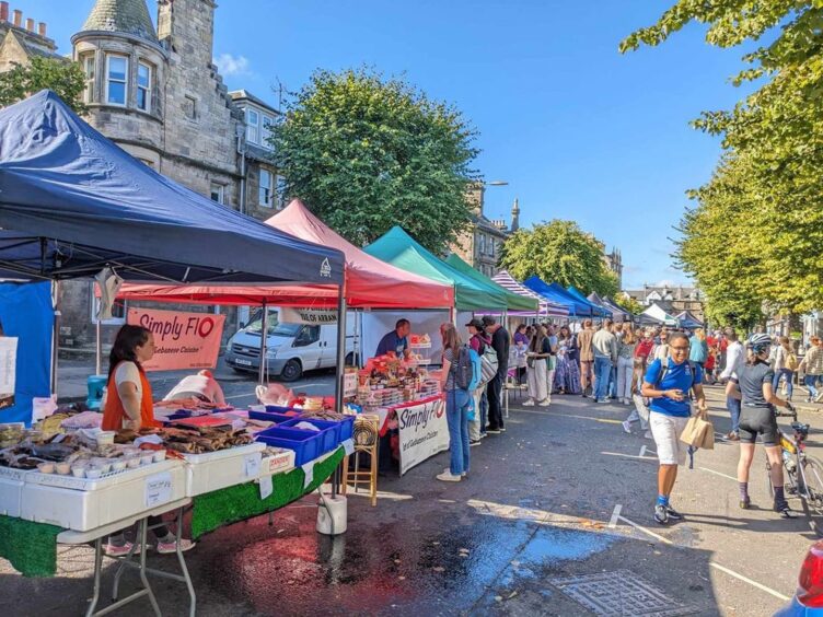 Image shows a general view of a sunny market on South Street in St Andrews.