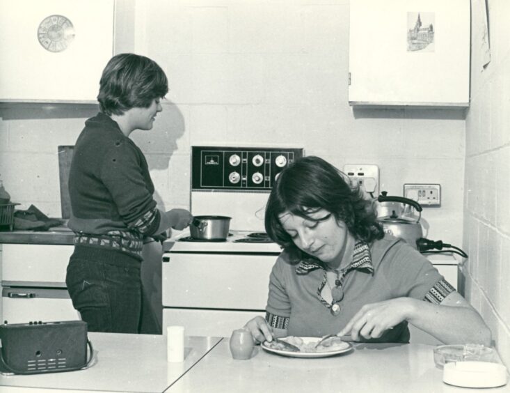 Image shows: A black and white picture of two students in the kitchen area of their accommodation at Stirling University. 