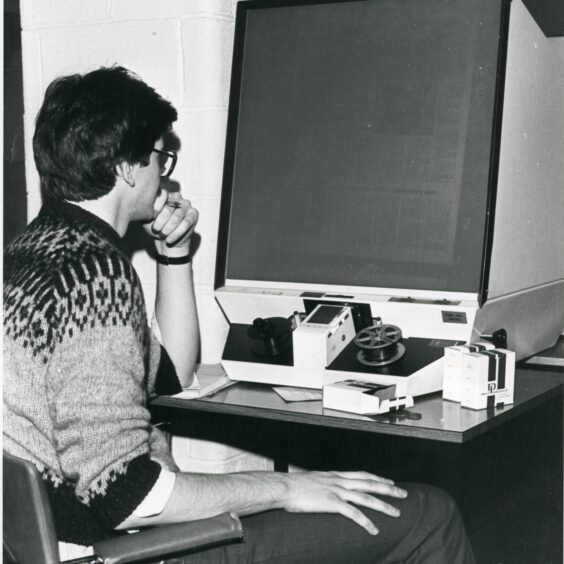Image shows: A man using a microfiche machine to look at old newspapers. Stirling 1980s