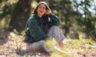 Anabel Wilson sitting barefoot in the grass smiling at the camera