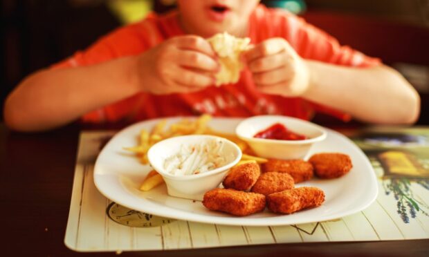 Child eating french fries with nuggets