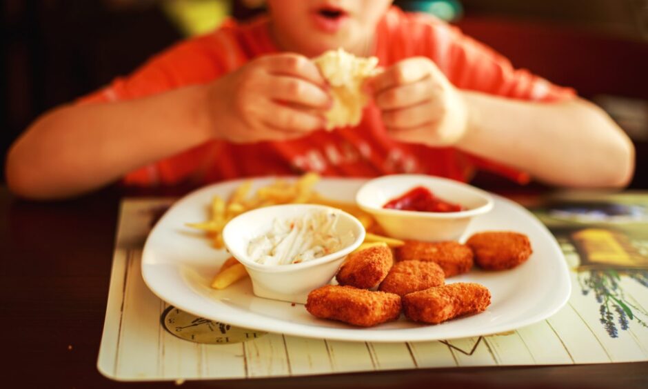 Child eating french fries with nuggets