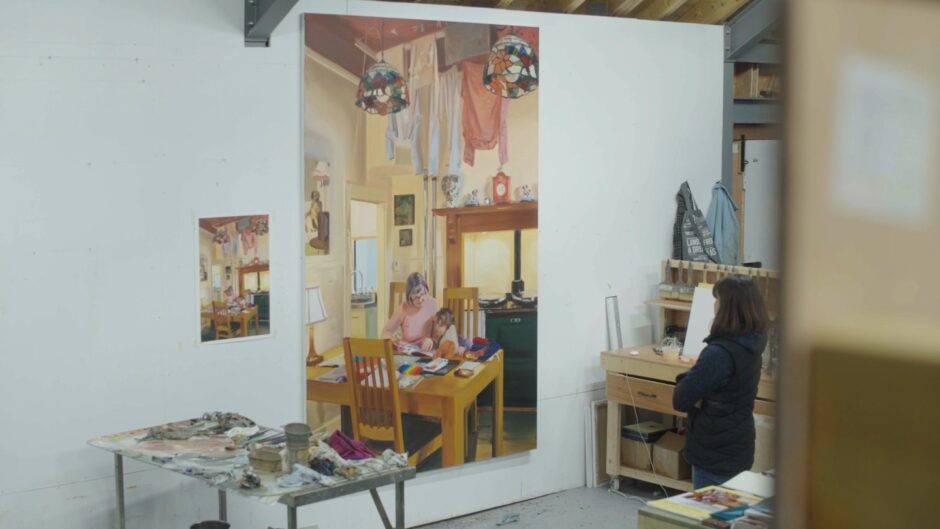 Image shows: Artist Caroline Walker in her Inverkeithing Studio. The artist is looking at a large scale painting of a grandmother and grandchild.