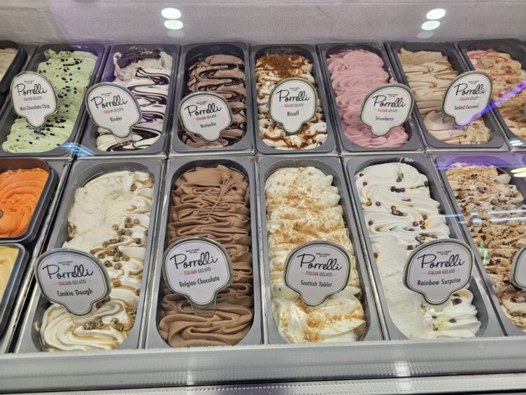 Several types of ice cream sitting in tubs behind a counter. 