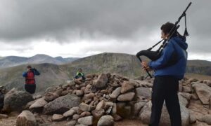 Joel Davey atop a Munro, playing his favourite song Highland Cathedral. Image: Joel Davey
