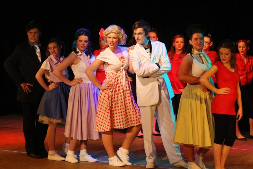 Braeview Academy's cast of Hairspray on stage in costume