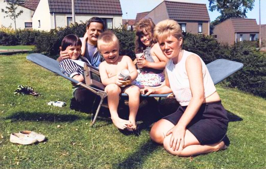 A family gathers around a sun longer in a Dundee garden.