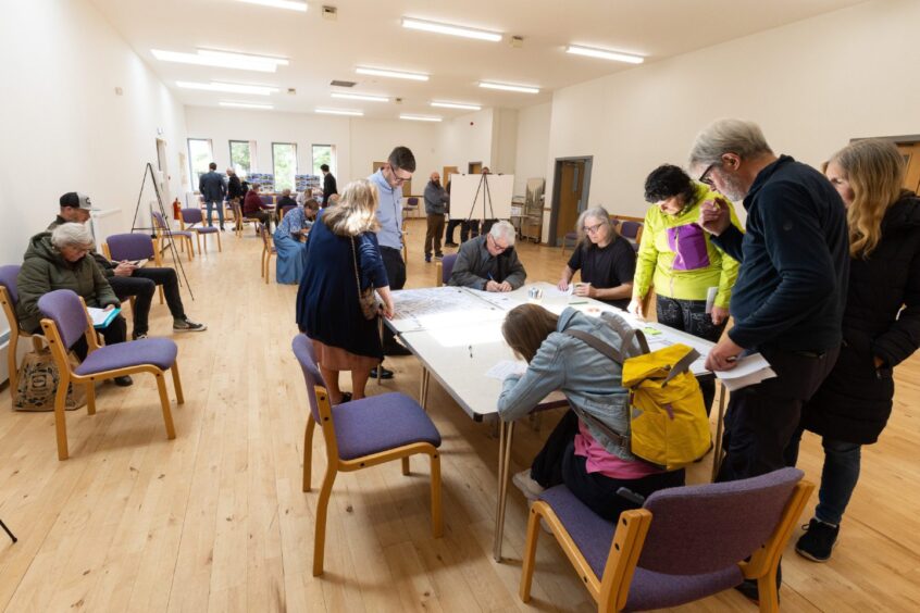 People crowded round a table at a public workshop. 