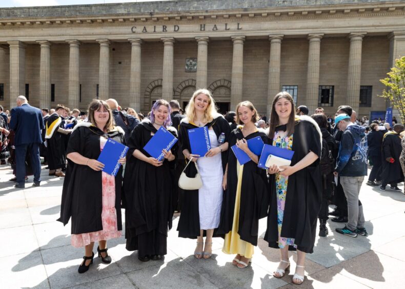 Five women in gowns pose in City Square. 