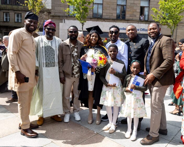 A female graduate flanked on either side by proud friends and family members. 
