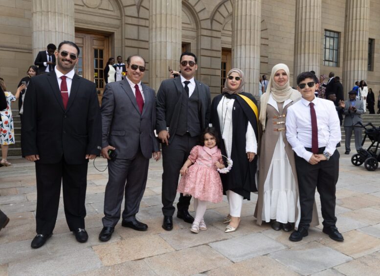 A female graduate flanked on either side by proud family members. 