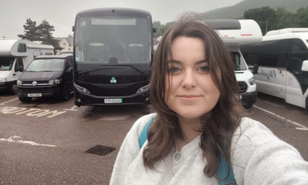 A female reporter posing in front of a bus.