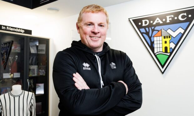 Dunfermline Athletic boss Neil Lennon stands with his arms folded in front of Pars memorabilia.