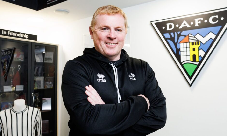 Dunfermline Athletic boss Neil Lennon stands with his arms folded in front of Pars memorabilia.