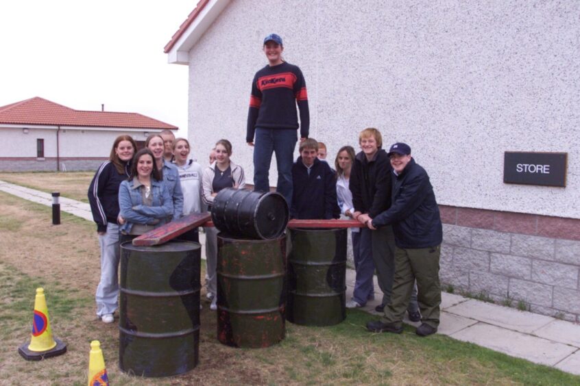 A character building exercise at Barry Buddon in August 2003 sees one pupil on a walkway across three barrels while others look on.