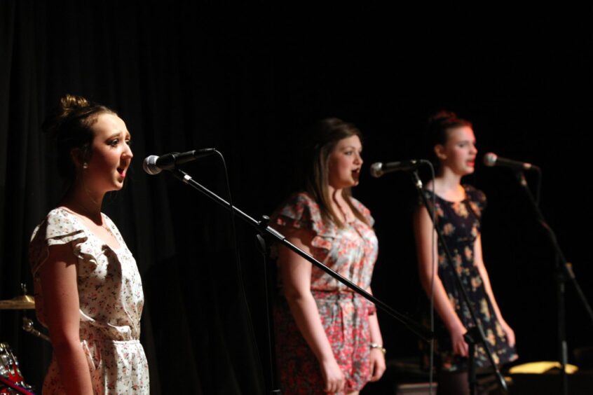 The group Breathless, which is three girls, take to the stage. 
