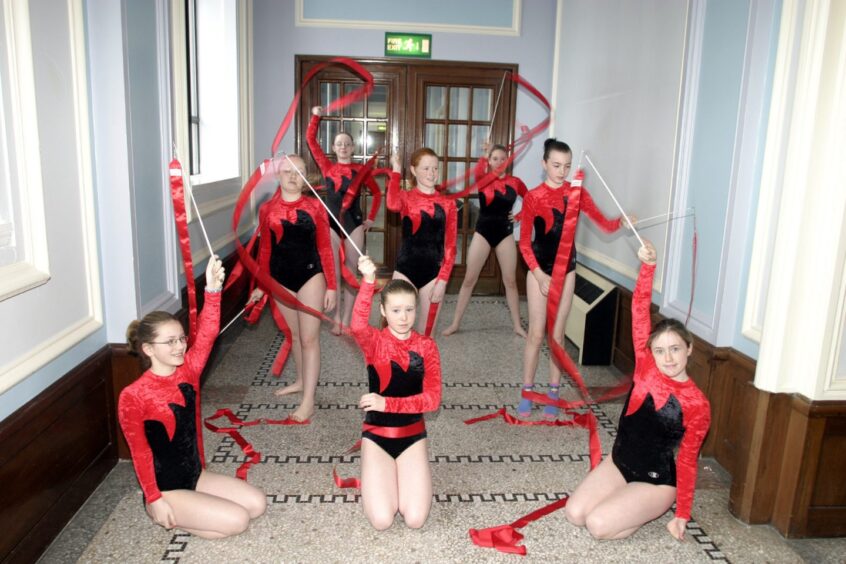 Braeview gymnasts twirl ribbons in a corridor.