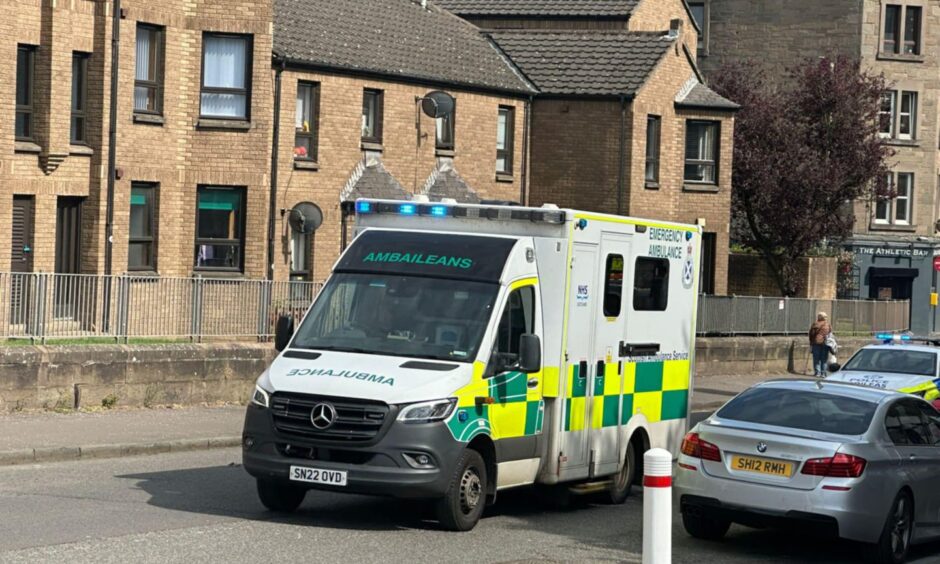 An ambulance with its sirens on leaving the scene. 