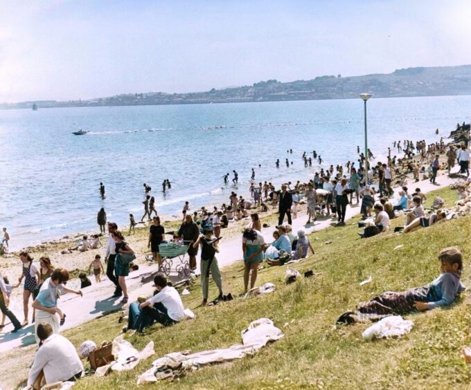 People walking on a path as others sunbathe at Broughty Ferry in 1971. 