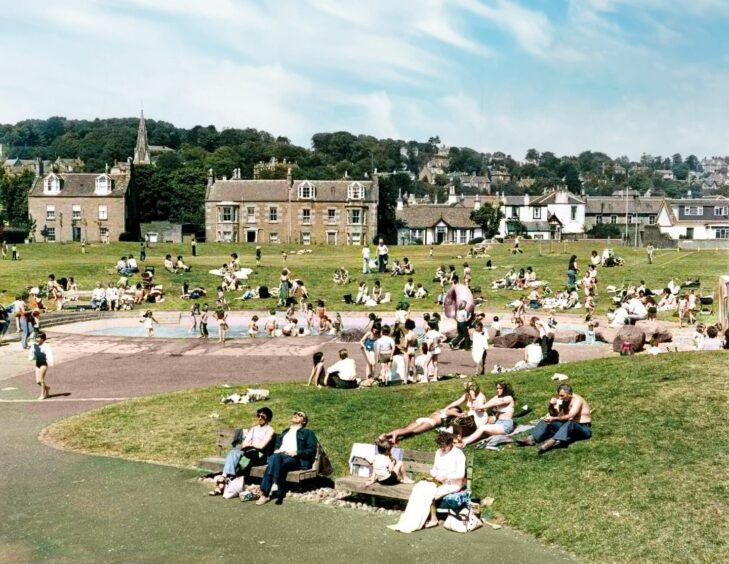 People on the grass around the outdoor pool, soaking up the sun at Castle Green in Broughty Ferry.
