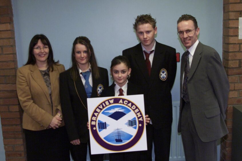 First-year Braeview Academy pupil Nicole McLeod holds up a sign showing her design for a new school badge, joined by fellow pupils and staff