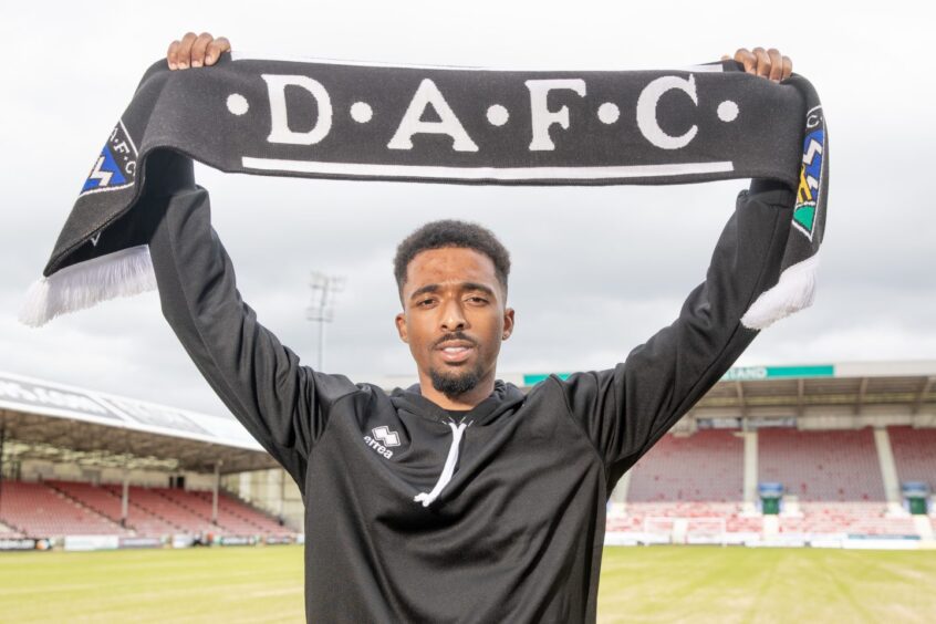 Tashan Oakley-Boothe holds up a DAFC scarf after signing his new deal.