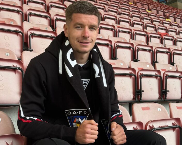 Charlie Gilmour sits in the East End Park stand and holds a Dunfermline Athletic scarf round his neck.