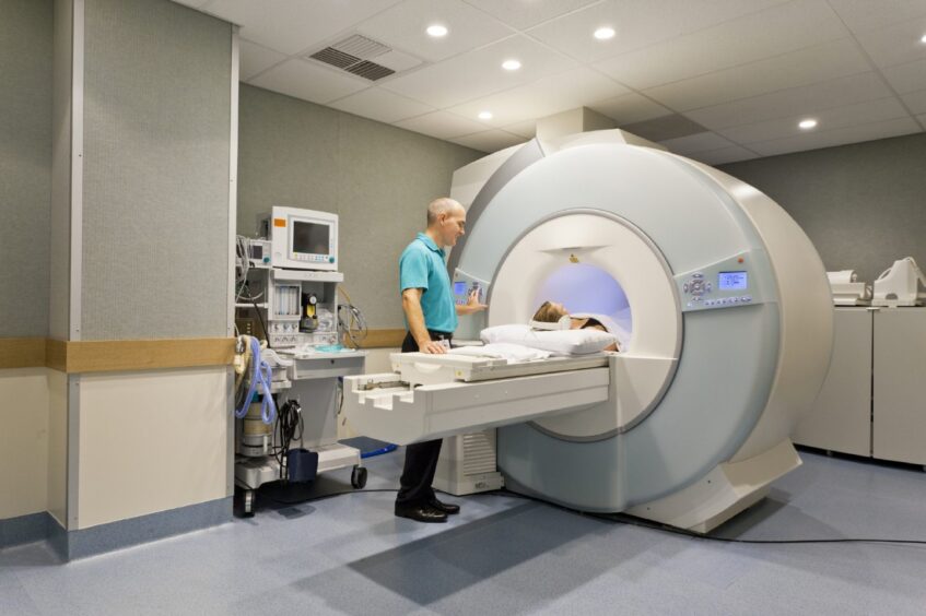 A patient undergoing a CT scan as a hospital worker looks on. 