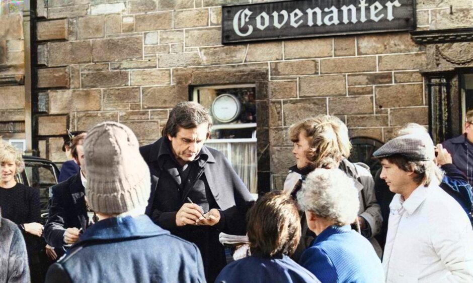 Johnny Cash is surrounded by fans while signing autographs outside the Covenanter Hotel in Falkland, Fife.