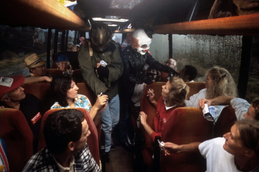 The Clown and the Wolfman walk down the aisle while holding up a tourist coach in Restless Natives. 