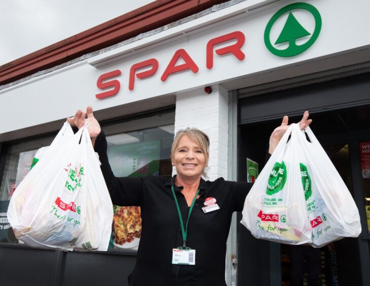 Lady holding up bags of goods outside SPAR Scotland store