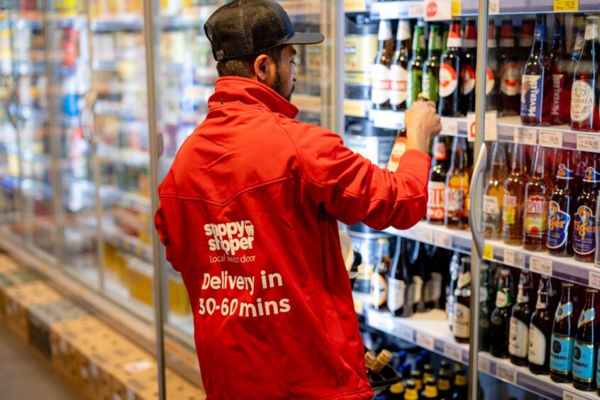 man shops for bottles of alcohol at a convenience store