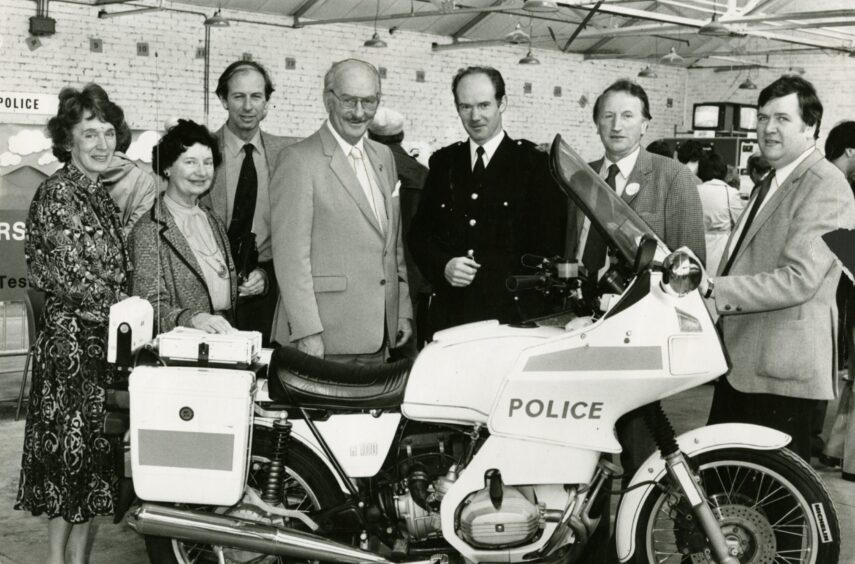 people gather around a police motorbike at the police stand at the Dundee Motor Show in 1983.