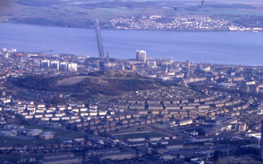 an ariel picture from 1988 showing houses, Dundee Law and the Tay Road Bridge, with the Fife coast in the distance.